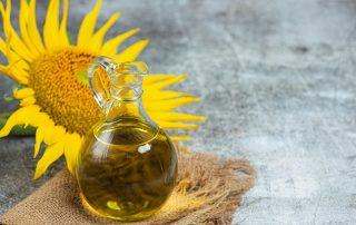 Aceite de girasol alto oleico en una jarra con un girasol de fondo